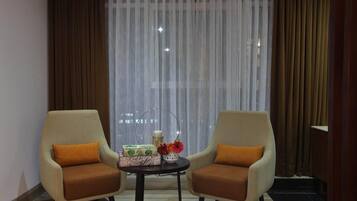 Una habitación con dos sillones, una mesita y un ventanal con cortinas traslúcidas.