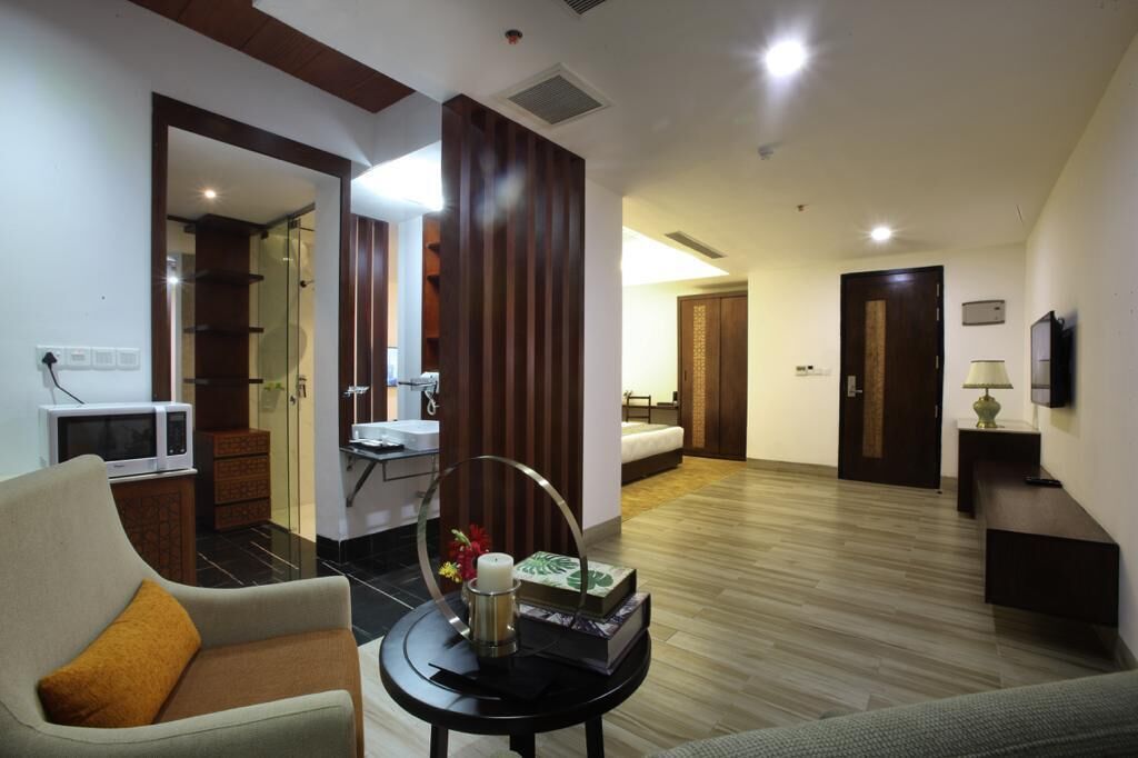 A modern living room with a sofa, a coffee table with decorative items, a television, and a bathroom visible through an open door.