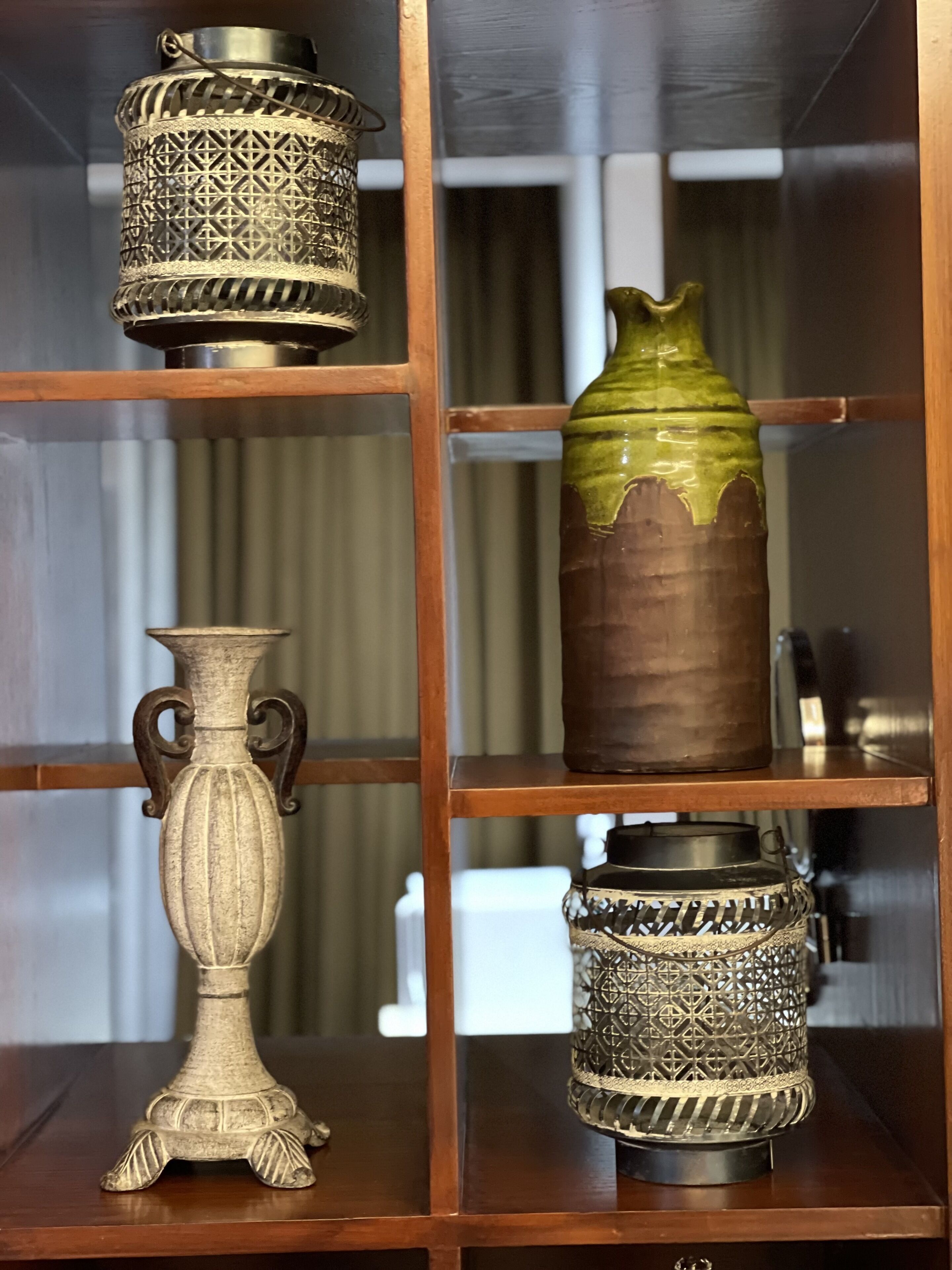 A wooden display cabinet with four shelves, each holding a different decorative item.