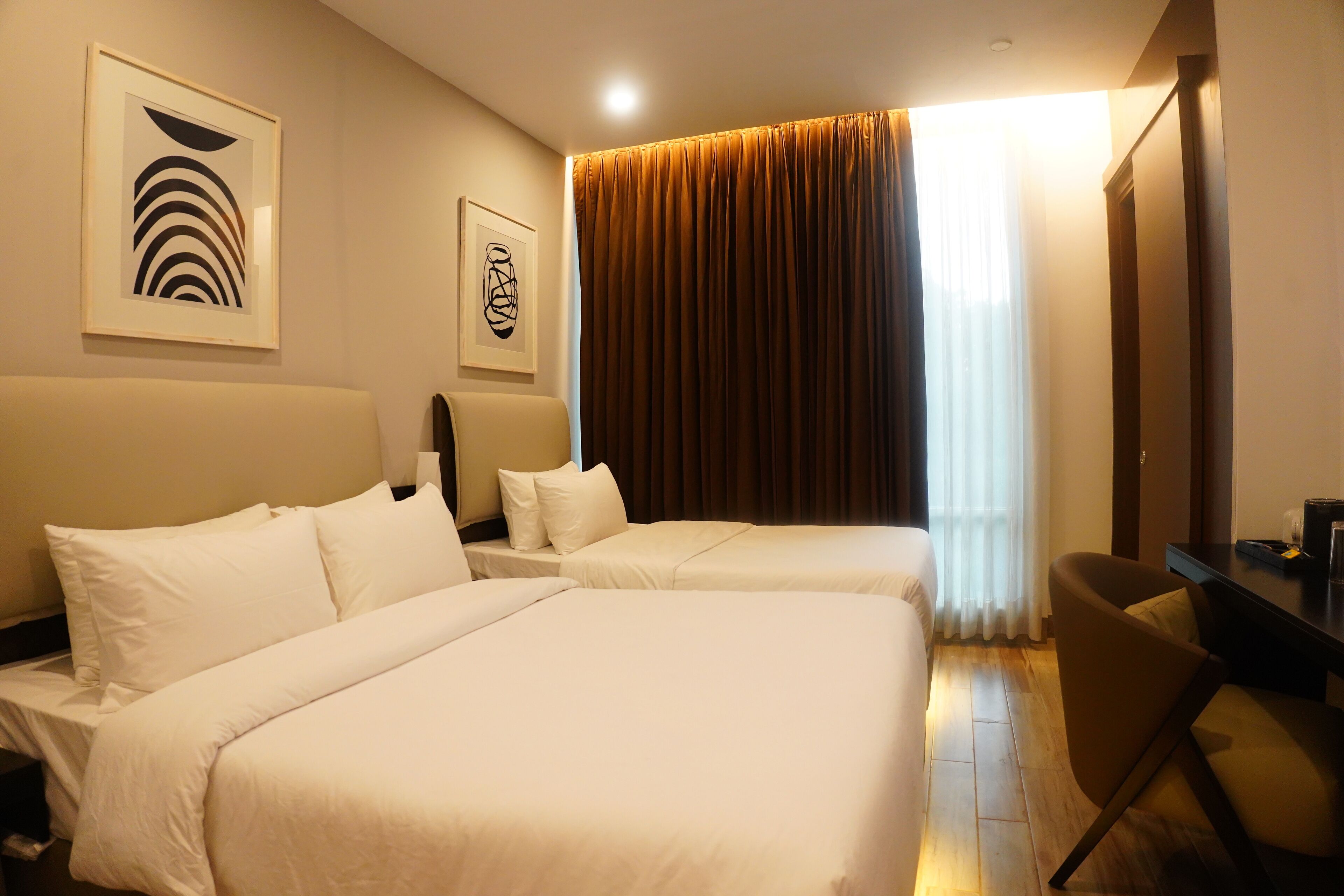 Habitación de hotel con dos camas, un escritorio y una silla.