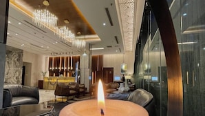 A modern lobby with a large lit candle centerpiece, leather seating, and contemporary decor. - Empyrean Hotel (Dhaka)