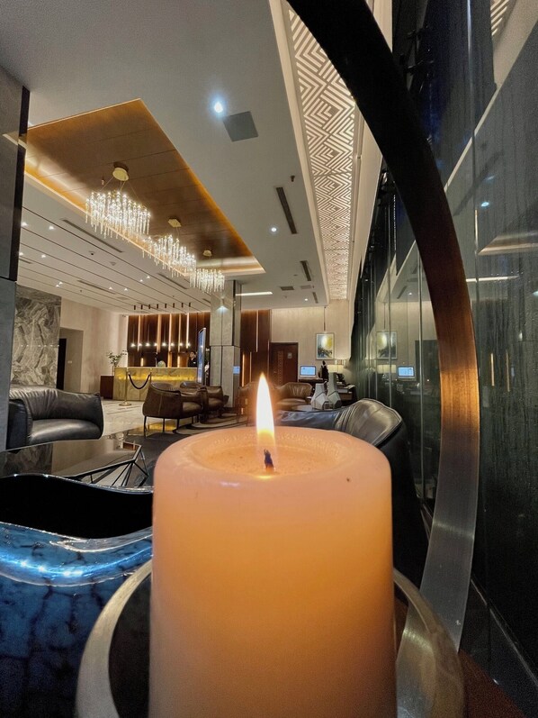 A modern lobby with a large lit candle centerpiece, leather seating, and contemporary decor.