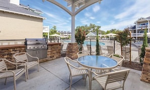 Relax by the pool with a meal prepared on the barbecue grill, surrounded by a patio with a table and chairs.
