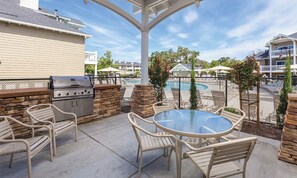 Relax by the pool with a meal prepared on the barbecue grill, surrounded by a patio with a table and chairs.