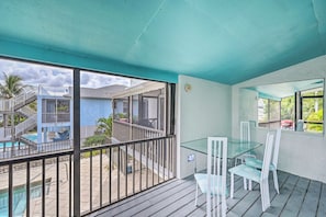 Un balcón con mesa y sillas de vidrio, una piscina y vistas de un edificio con escaleras.