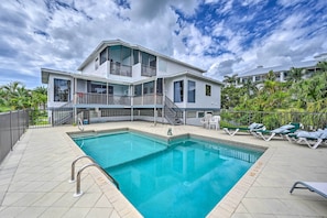 Una casa de dos pisos con piscina y balcón.