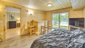 Puuinen mökki, jossa on sänky, televisio ja työpöytä.