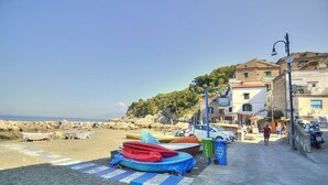 A beach with boats, a clear sky, and buildings in the background. - Appartamento Naia A: A graceful apartment located right on the beach, with Free WI-FI. (Sorrento)