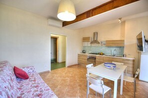A compact living space with a kitchenette, a dining area with a table and chairs, and a sofa with a red pillow. - Appartamento Naia B: A graceful apartment located right on the beach, with Free WI-FI. (Sorrento)