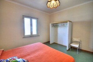 Quarto com cama, janela, guarda-roupa e uma cadeira.
