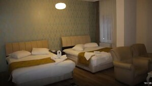 A hotel room with two beds, a chair, and a small table. - Park Otel (Kayseri)