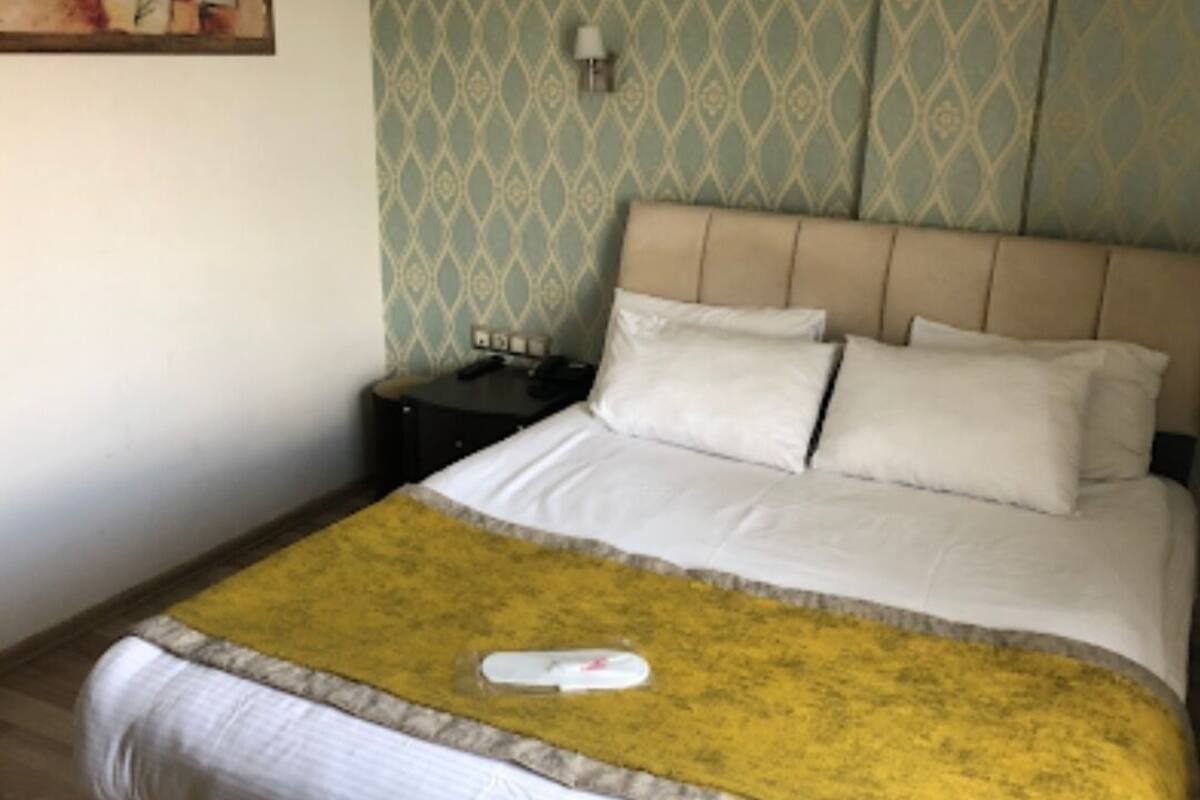 A neatly made bed with a yellow throw blanket and white bedding.
