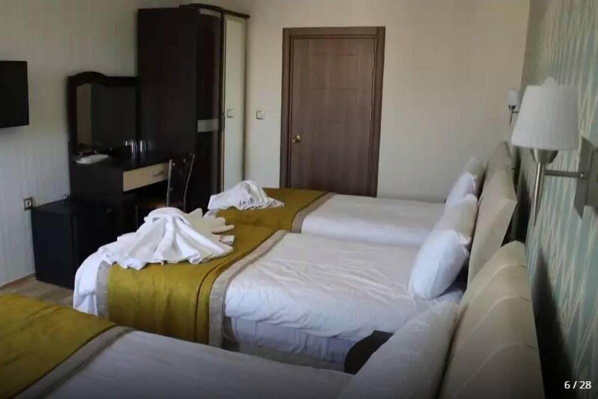 A hotel room with two beds, a wardrobe, a desk, and a television.