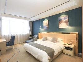 Una habitación de hotel moderna con una cama grande, mesitas de noche, un escritorio y una silla.