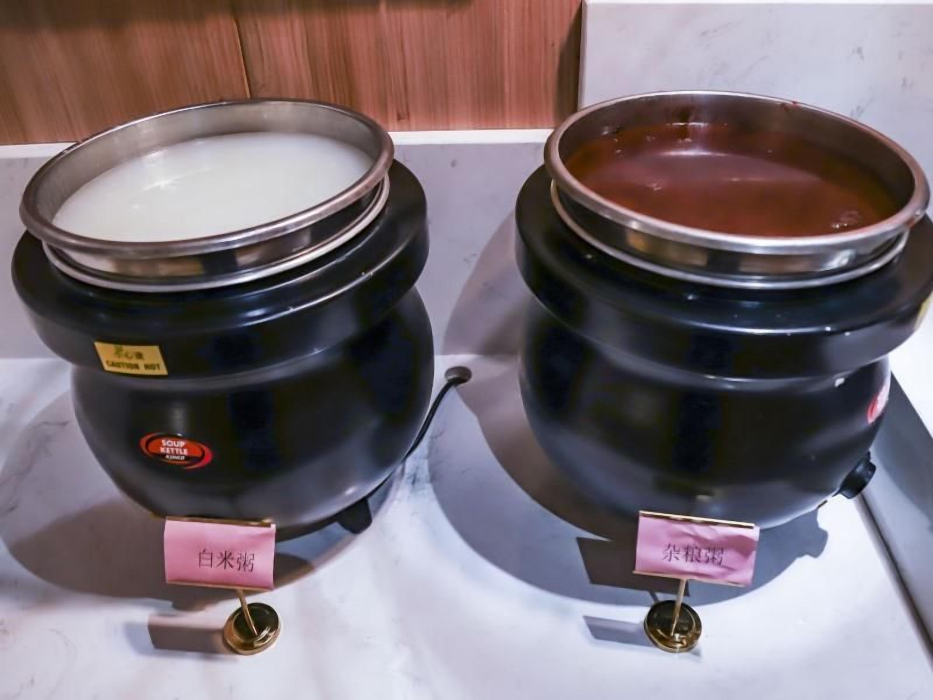 Dos recipientes negros con tapas metálicas, cada uno con una pequeña etiqueta y un asa dorada.