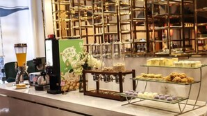 A cafe counter with a coffee machine, a menu board, and various pastries displayed on shelves.
