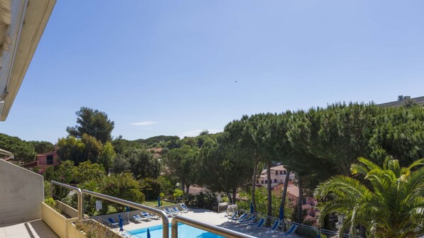 A pool area with lounge chairs and a view of a mountainous landscape.