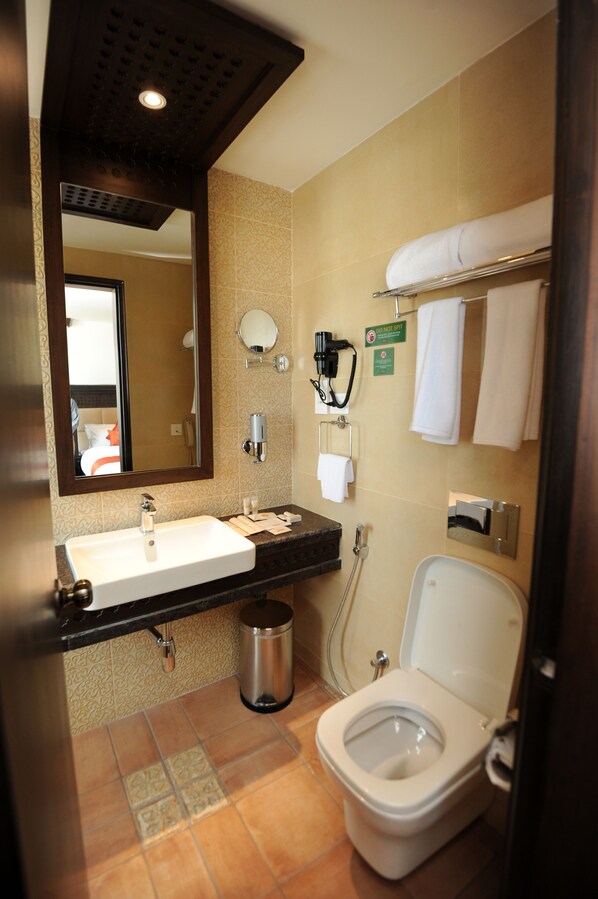 A hotel bathroom with a sink, mirror, toilet, towel rack, and a trash can. - Kantipur Village (Kathmandu)