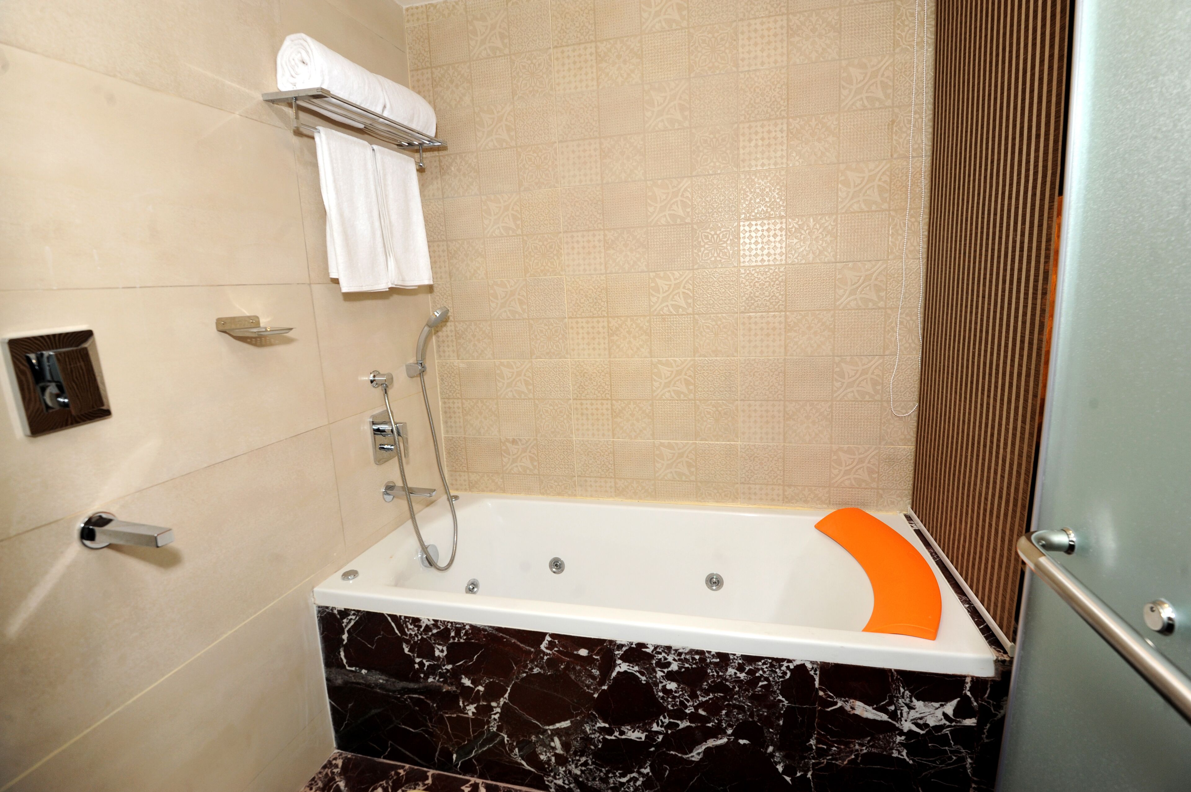 A bathroom with a bathtub, a towel rack, and a showerhead.