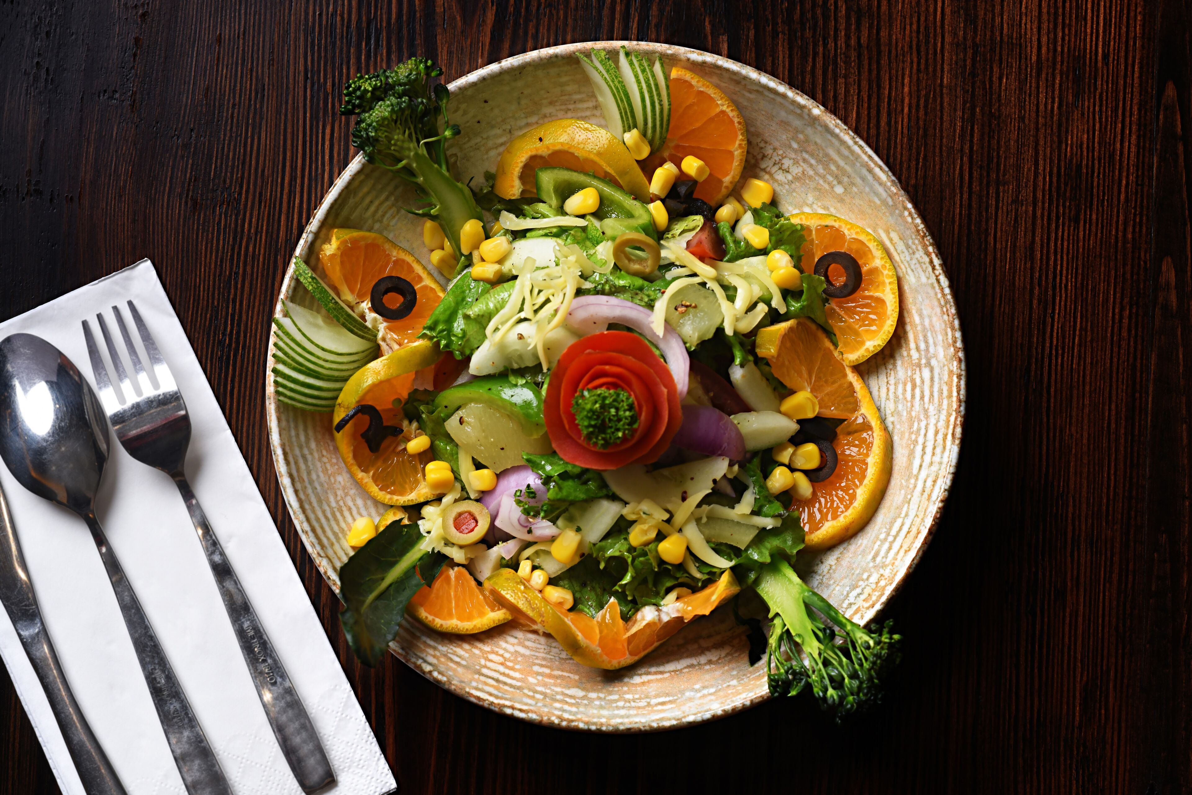 A plate of colorful salad with various vegetables and fruits.