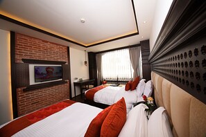 A hotel room with two beds, a brick wall, a television, and a window with curtains. - Kantipur Village (Kathmandu)
