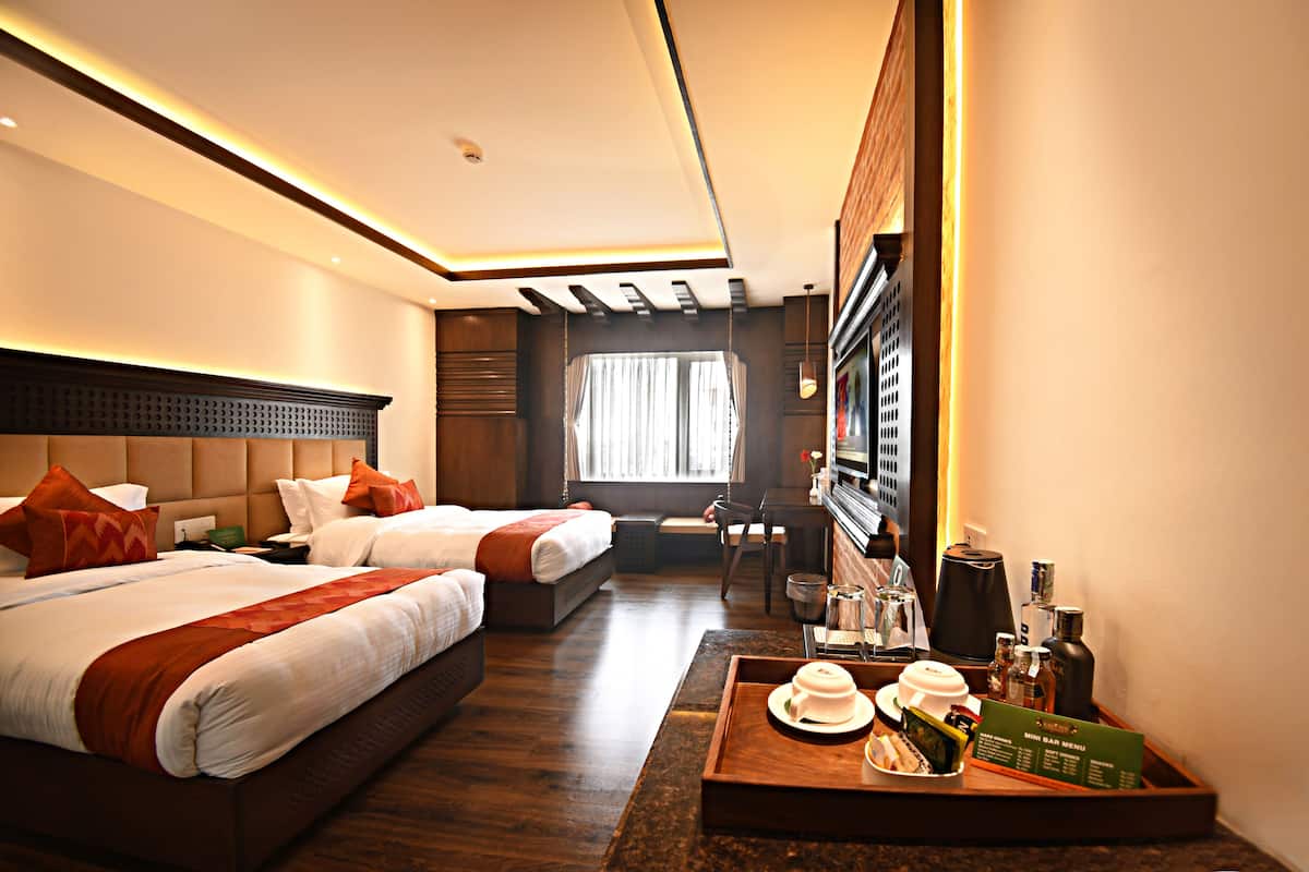 A hotel room with two beds, a desk, a chair, a coffee tray, and a minibar.