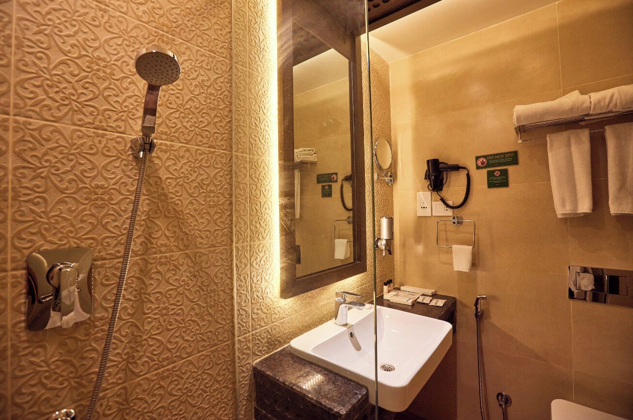 A bathroom with a shower, sink, and towel rack.