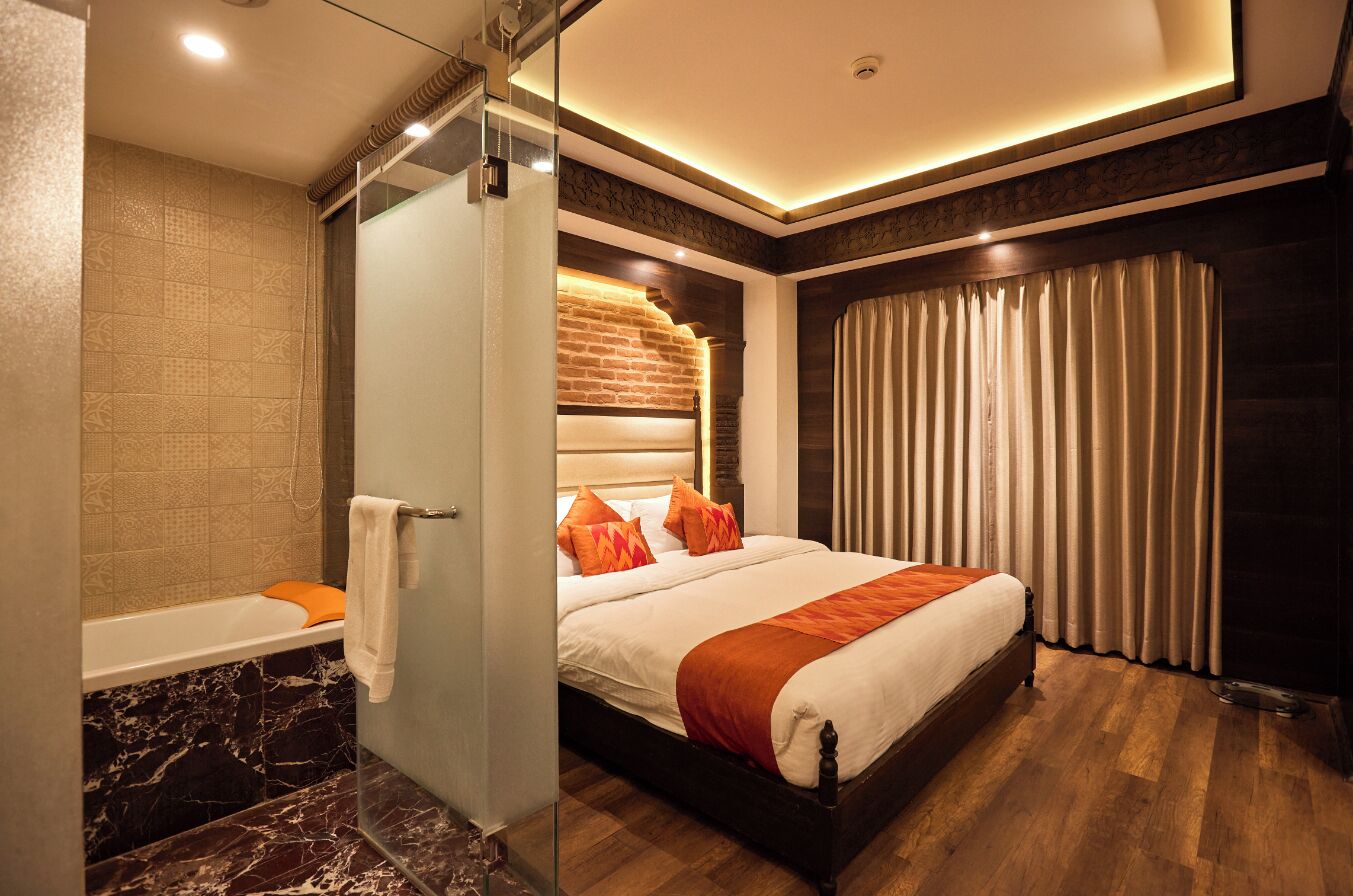 A modern hotel room with a large bed, a separate bathroom, and a view of the city.