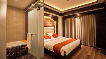 A modern hotel room with a large bed, a separate bathroom, and a view of the city.