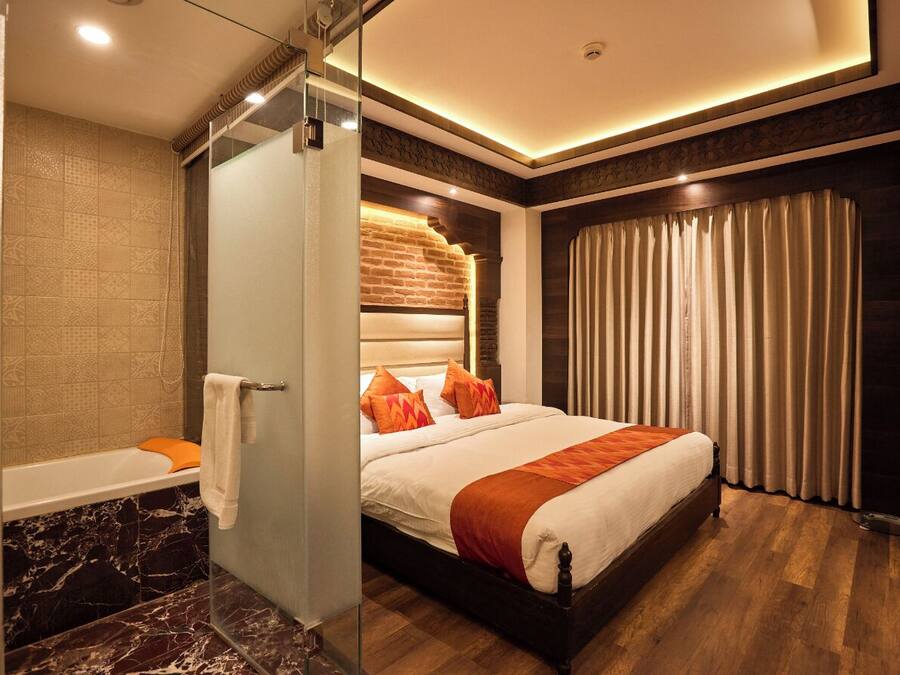 A modern hotel room with a large bed, a separate bathroom, and a view of the city.