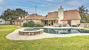 Ein Wohngrundstück mit Swimmingpool, überdachter Terrasse und einem Ziegelhaus.