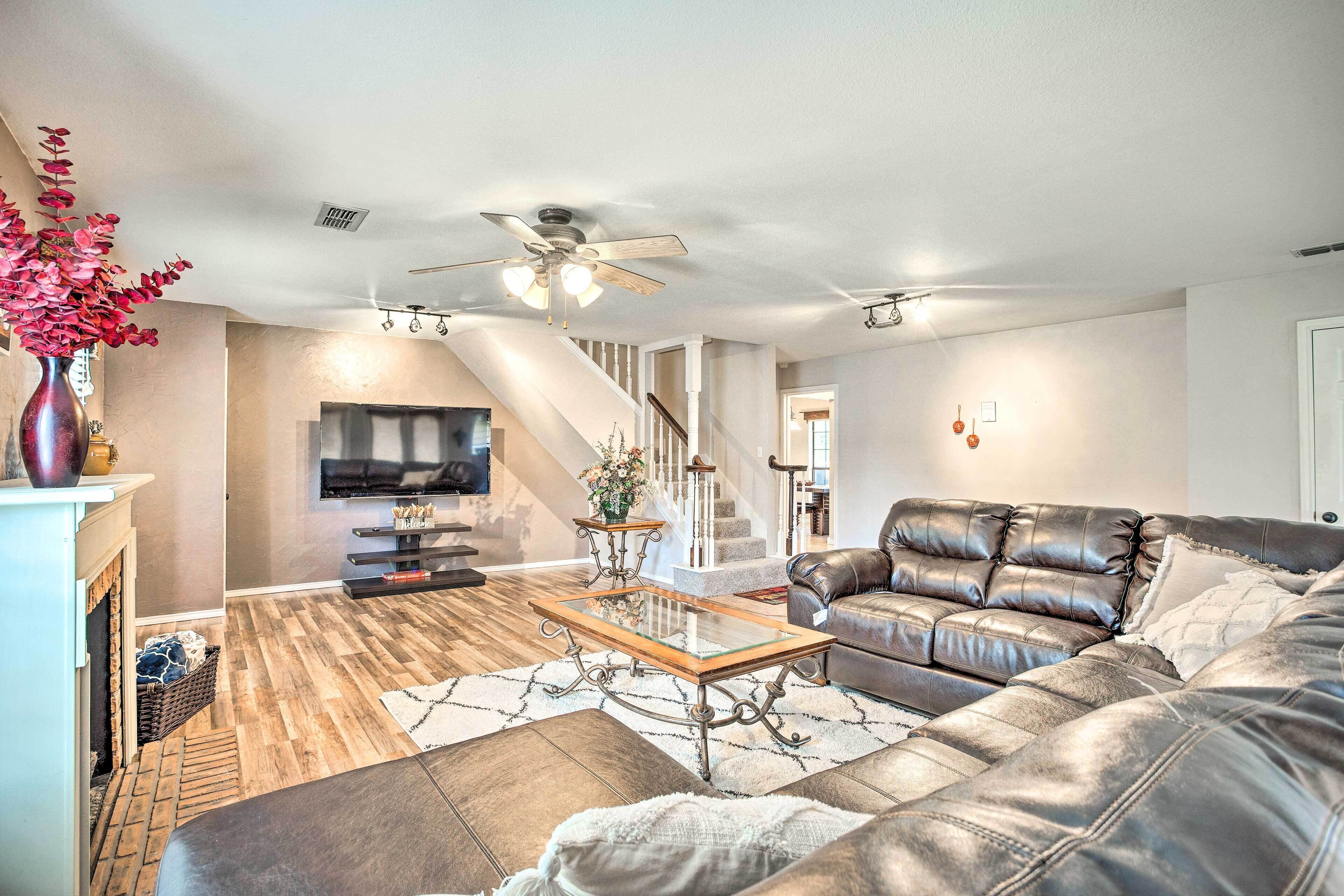 A spacious living room with a leather sofa, a glass coffee table, and a fireplace.