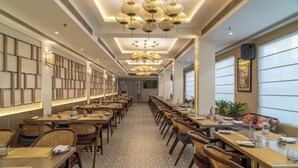 A spacious restaurant with long tables, wicker chairs, and hanging spherical light fixtures. - Regenta Place Amritsar (Amritsar)