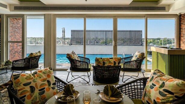 A dining area with a view of a swimming pool, large windows, and outdoor seating. - Regenta Place Amritsar (Amritsar)