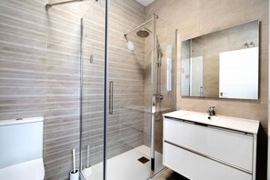 Une salle de bain moderne avec une douche à parois de verre, un lavabo blanc et un grand miroir.