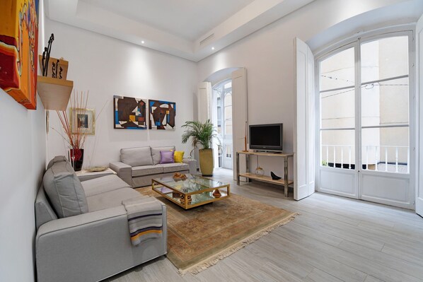 Un salon moderne avec un canapé, une table basse, un téléviseur et des œuvres d’art accrochées aux murs.