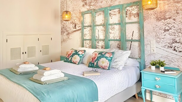 Quarto com cama, mesa de cabeceira, guarda-roupa e teto com design de palha.