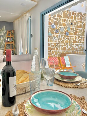 A dining area with a stone wall, a wooden ladder bookshelf, and a view of the outside. - Holiday Home "Recuerdos del Sur" with Pool, Terrace, Balcony, BBQ, A/C & Wi-Fi (El Gastor)