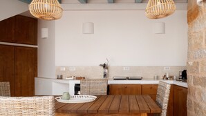 Una cocina con armarios de madera, una mesa de madera, sillas de mimbre y dos lámparas colgantes de mimbre.