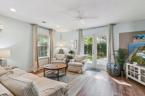 A living room with a sofa, armchairs, a coffee table, and a television.