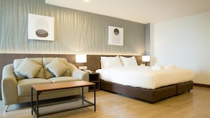 Quarto de hotel com uma cama, um sofá, uma mesa de cabeceira e uma mesa.