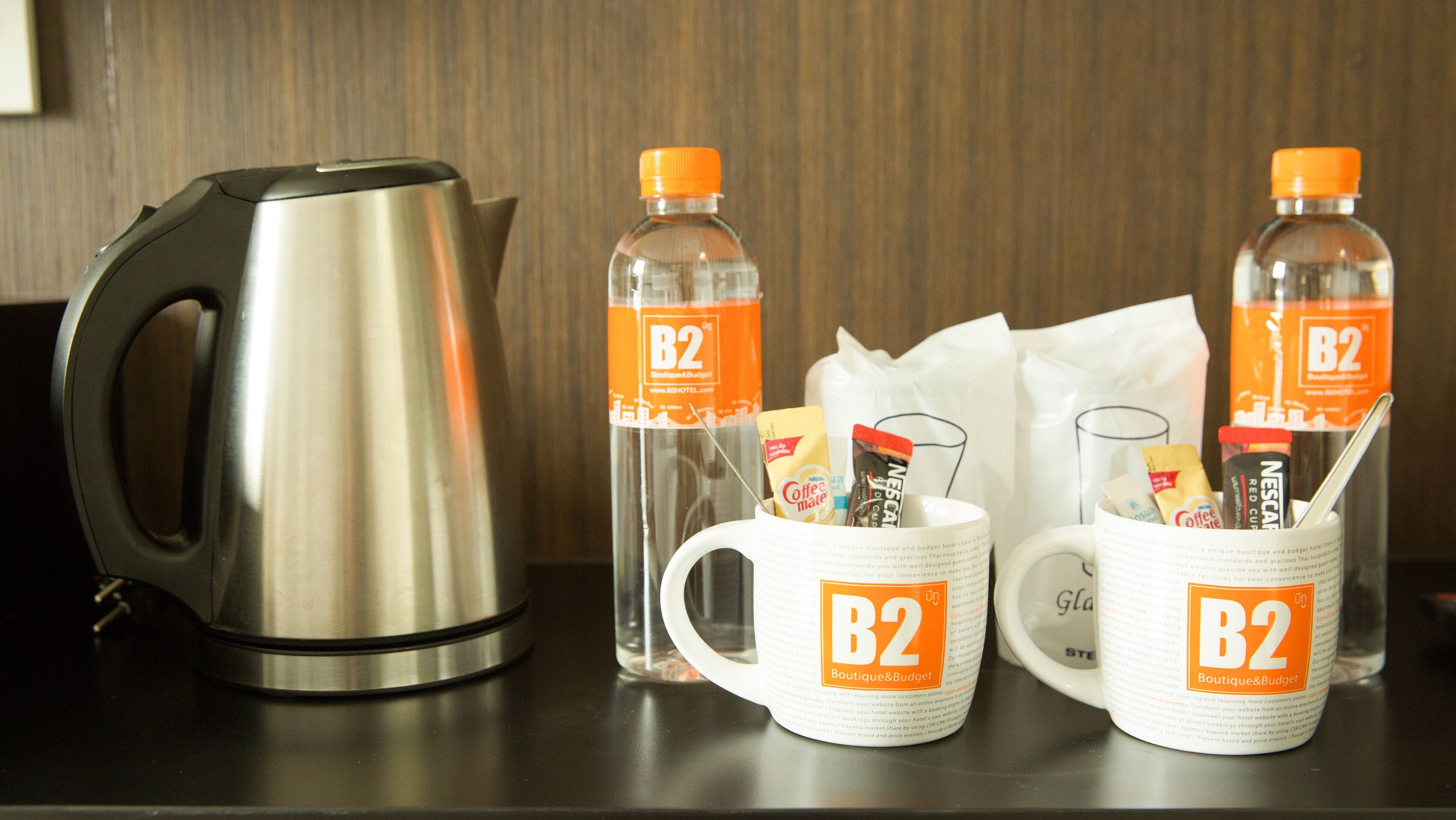 A kitchen area with a kettle, two coffee mugs, and two bottles of B2 coffee.