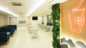 Decoração moderna com aviso de serviço 24 horas, áreas de estar e parede verde decorativa.