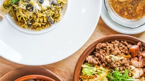 A variety of dishes including noodles, a salad with vegetables and meat, and a bowl with shredded carrots and a boiled egg.