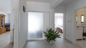 A hallway with a white door, a potted plant, and a wooden cabinet with a television. - Pure relaxation - country house with pool (Karojba)