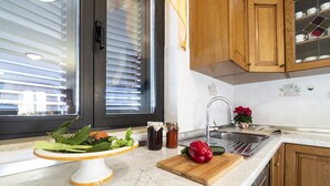 A kitchen with a marble countertop, wooden cabinets, a window with blinds, a sink, and a cutting board with vegetables. - Pure relaxation - country house with pool (Karojba)