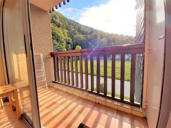 A balcony with a view of a green landscape and a mountain in the background.