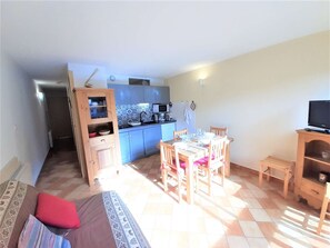 A compact living space with a dining area, kitchenette, and a TV.