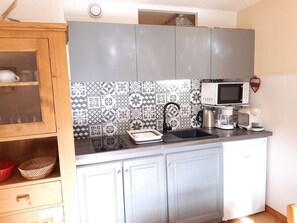 A modern kitchen with a patterned backsplash, a microwave, a coffee maker, and a kettle. - Charming T2 in Saint-Lary-Soulan with balcony, parking, and ski locker (Saint-Lary-Soulan)