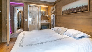 Ein Schlafzimmer mit einem großen Bett, Holzwänden, einer Dusche und einem Gemälde.
